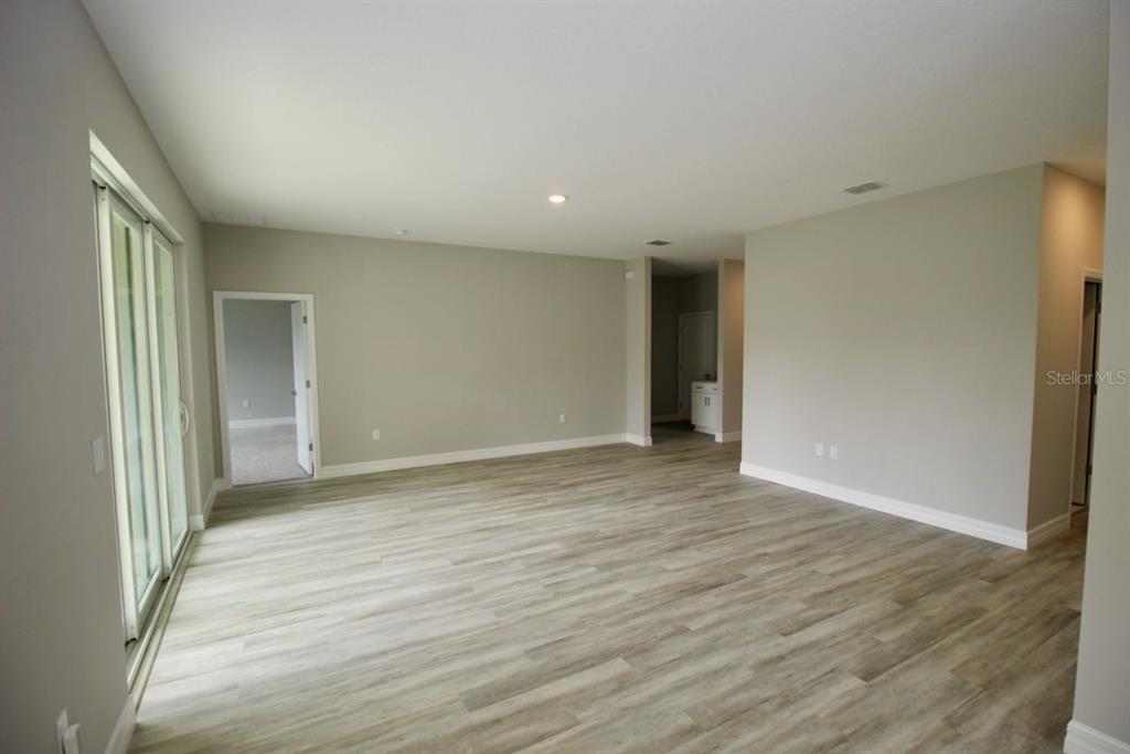 An empty room with light wood-look flooring, neutral walls, and sliding glass doors — 4175 POLYNESIA ROAD, NORTH PORT, FL