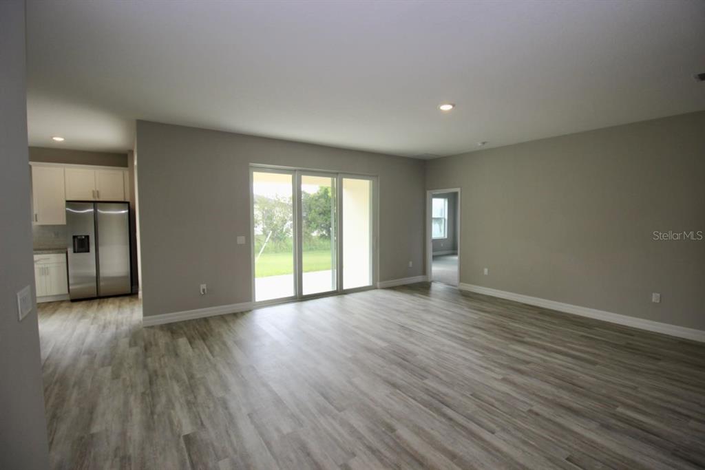 An open living area features light wood-look flooring, gray walls, and sliding glass patio doors — 4175 POLYNESIA ROAD, NORTH PORT, FL