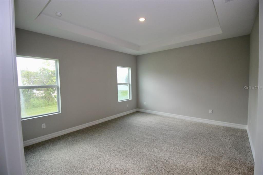 An empty bedroom features light gray walls, beige carpeting, and a tray ceiling — 4175 POLYNESIA ROAD, NORTH PORT, FL