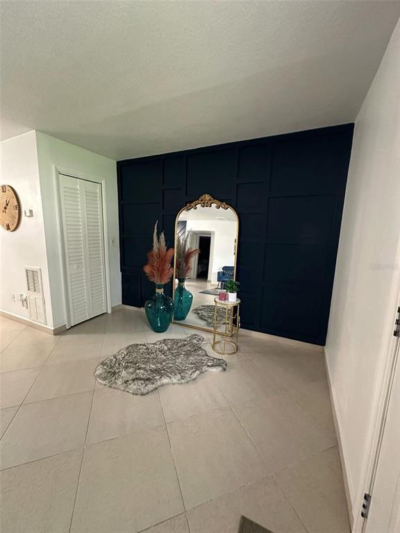 A room features a dark blue accent wall with molding, a gold-framed mirror, and tile flooring — 1211 LEHIGH STREET, KISSIMMEE, FL