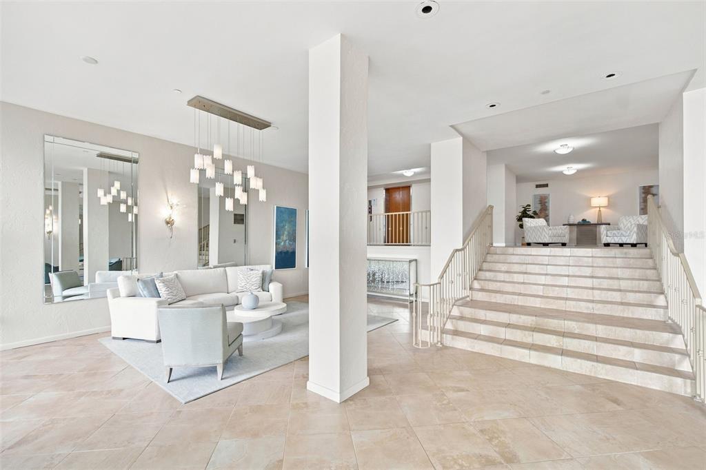 A spacious living area features a white sofa, a central pillar, and a tiled staircase — 707 S GULFSTREAM AVENUE UNIT 207, SARASOTA, FL
