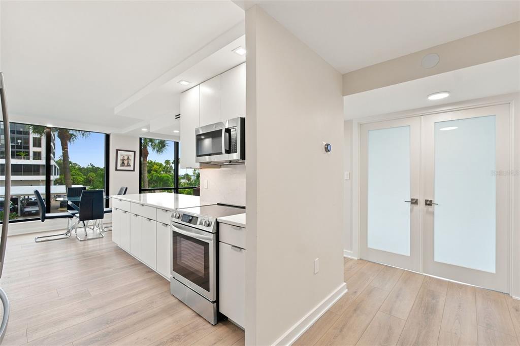 A modern kitchen with white cabinets and stainless steel appliances opens to a dining area — 707 S GULFSTREAM AVENUE UNIT 207, SARASOTA, FL
