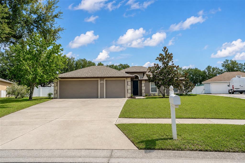 A single-story house with a three-car garage, a concrete driveway, and a white mailbox — 10105 LENOX STREET, CLERMONT, FL