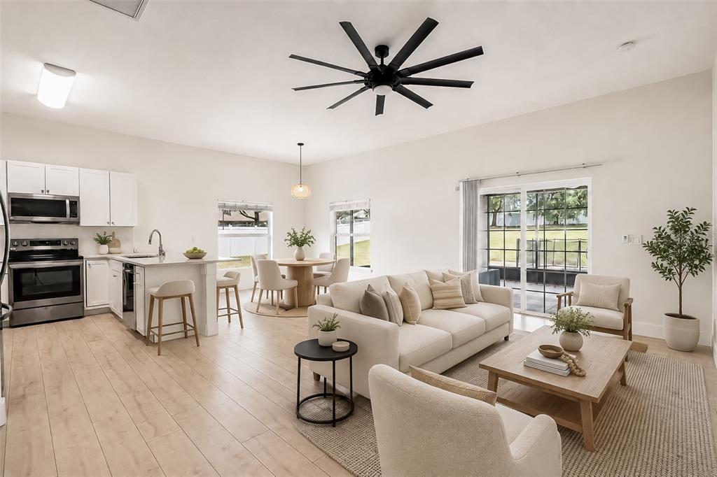 An open-concept kitchen, dining area, and living room featuring light wood floors and white cabinetry — 10105 LENOX STREET, CLERMONT, FL