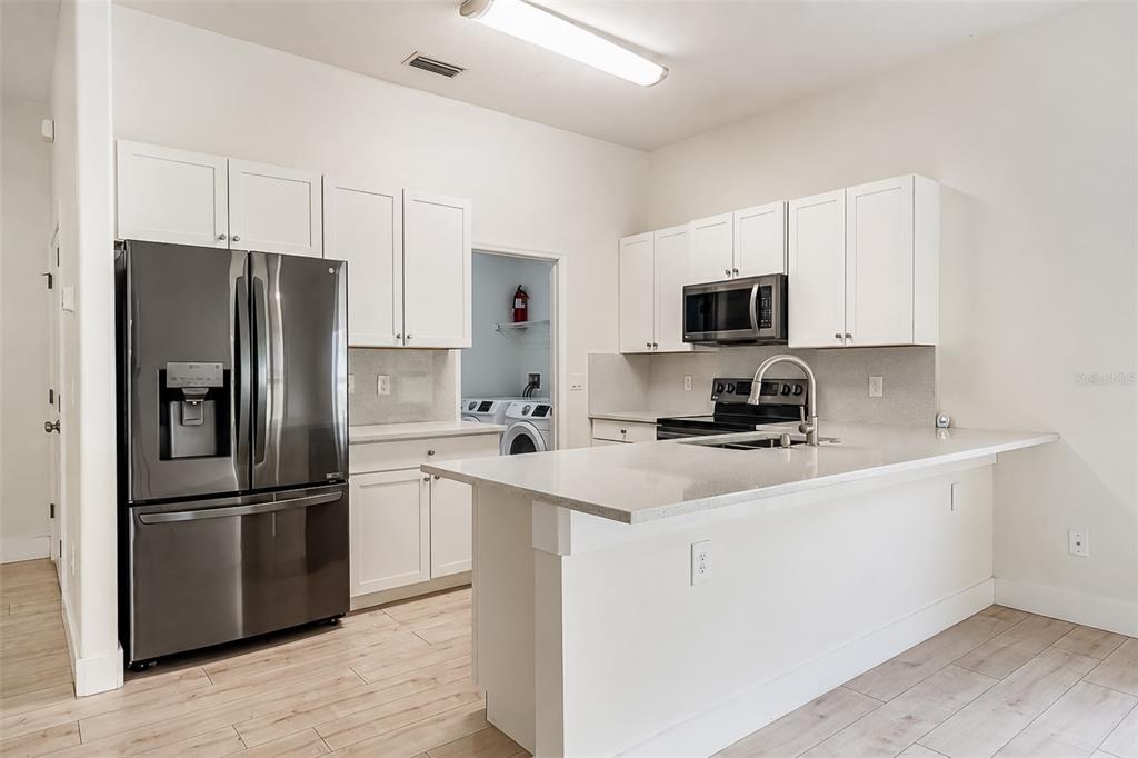 A modern kitchen features white cabinets, stainless steel appliances, and a quartz-topped island — 10105 LENOX STREET, CLERMONT, FL