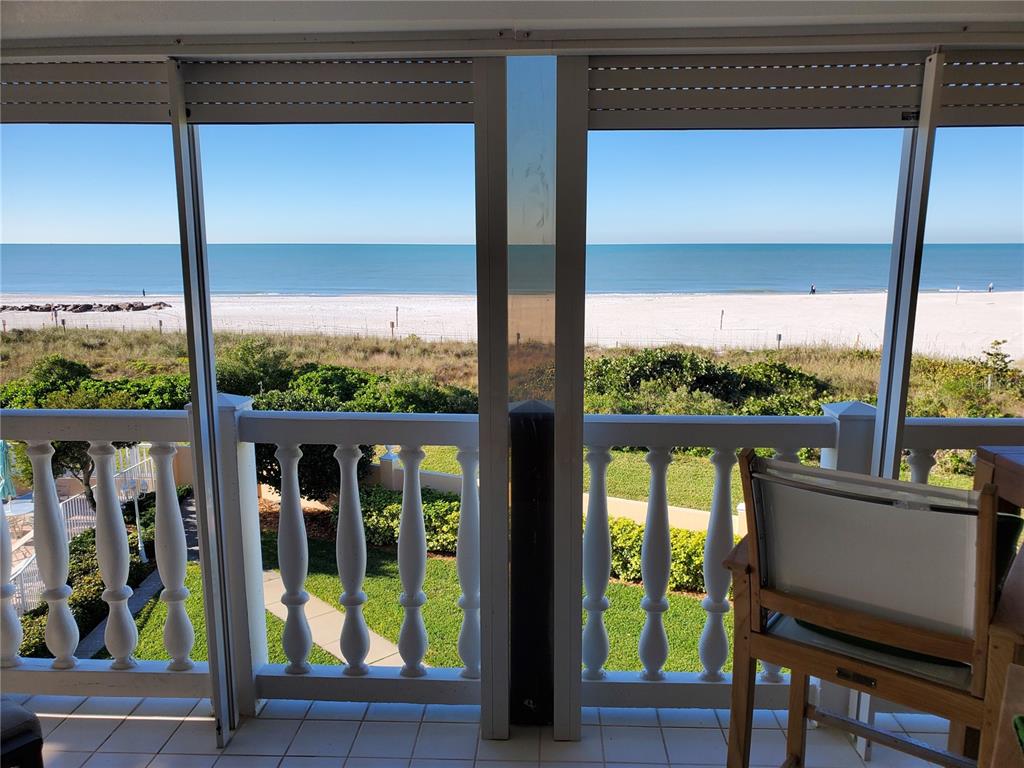 A balcony with white balustrades overlooks a sandy beach and the ocean — 6650 SUNSET WAY UNIT 220, ST PETE BEACH, FL