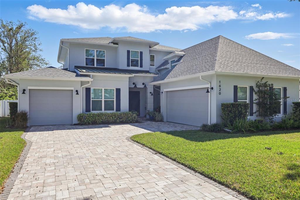 A two-story house with a paved driveway, two garage doors, and a light-colored exterior — 1620 PALM AVENUE, WINTER PARK, FL