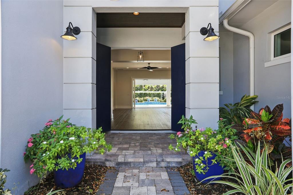 A paved entryway leads through dark blue doors into an open-concept home with pool views — 1620 PALM AVENUE, WINTER PARK, FL