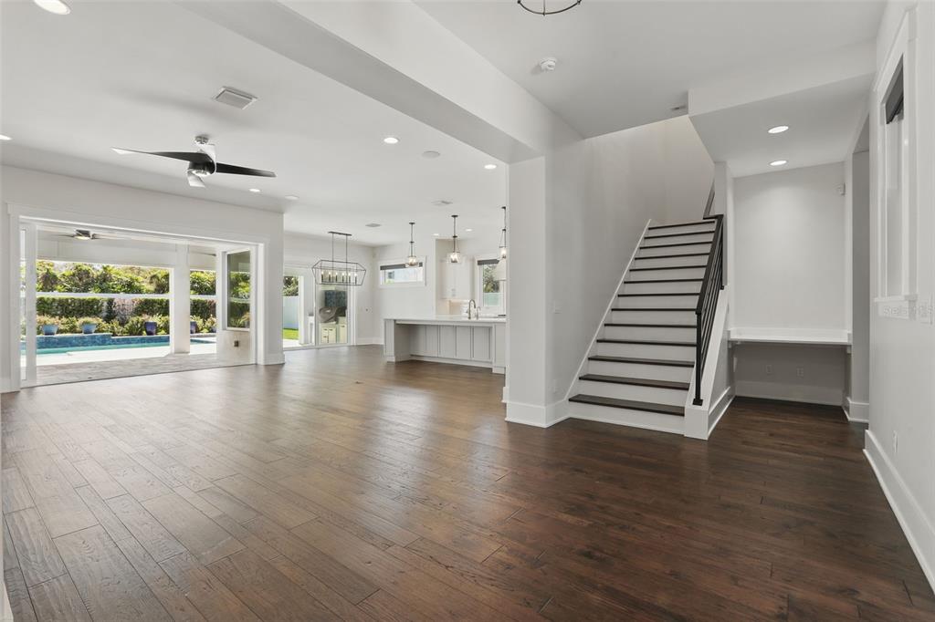 An open-concept living area with hardwood floors, a staircase, and a view of a pool — 1620 PALM AVENUE, WINTER PARK, FL