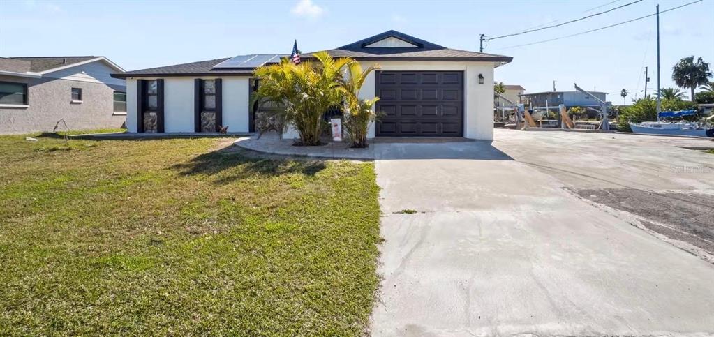 A single-story house with a dark garage door, solar panels, and a concrete driveway — 6712 SEA RANCH DRIVE, HUDSON, FL