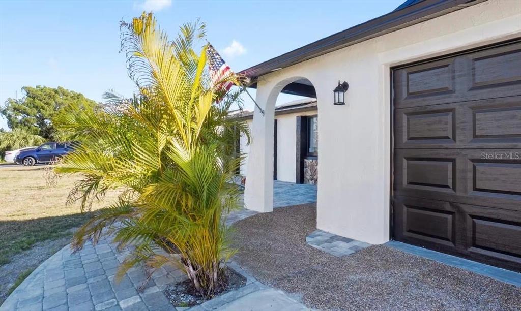 A palm tree stands in front of a white house with a dark garage door — 6712 SEA RANCH DRIVE, HUDSON, FL