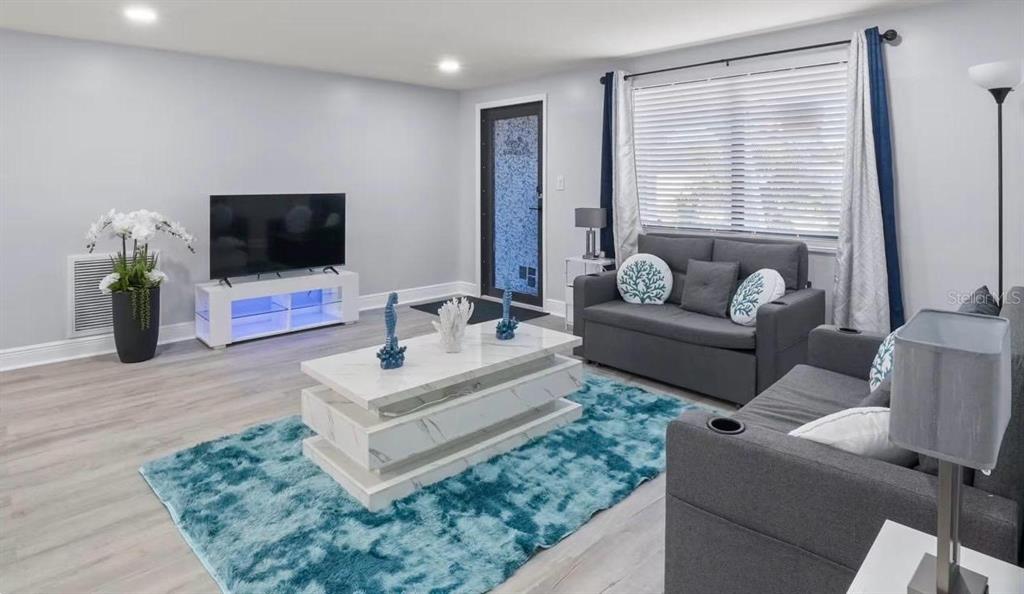 A living room features gray sofas, a white coffee table, and a blue area rug — 6712 SEA RANCH DRIVE, HUDSON, FL