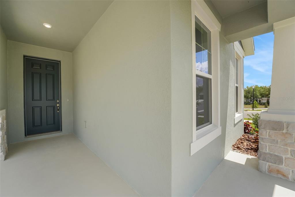 A covered front porch features a dark gray door, a window, and stone column accents — 13512 TURNLEAF BOULEVARD, PUNTA GORDA, FL