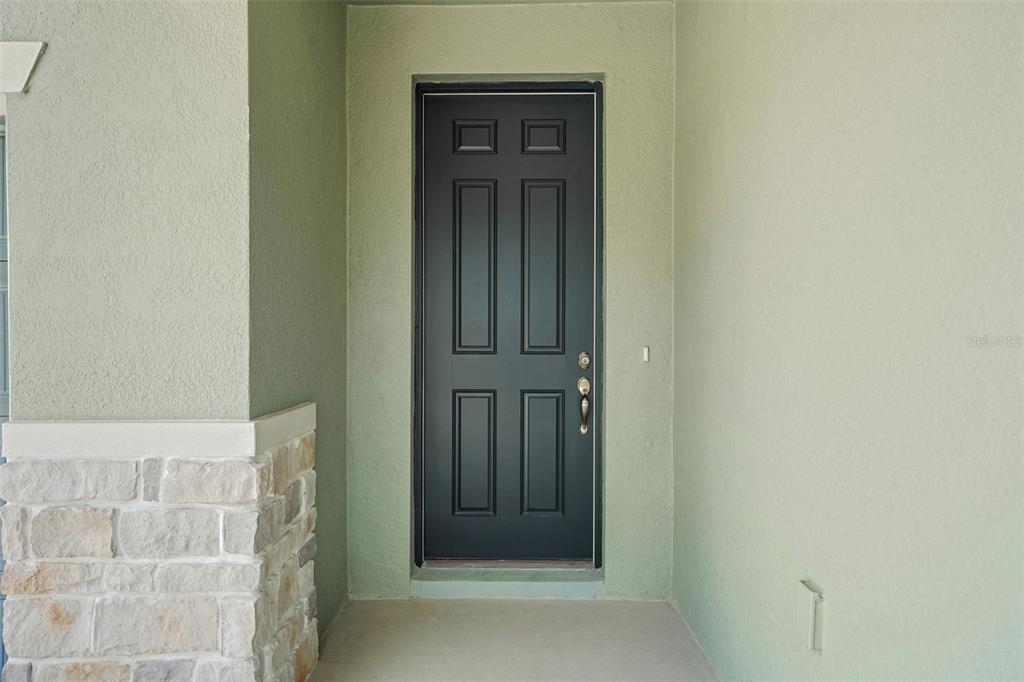 A black front door with a stone base sits on a covered porch — 13512 TURNLEAF BOULEVARD, PUNTA GORDA, FL
