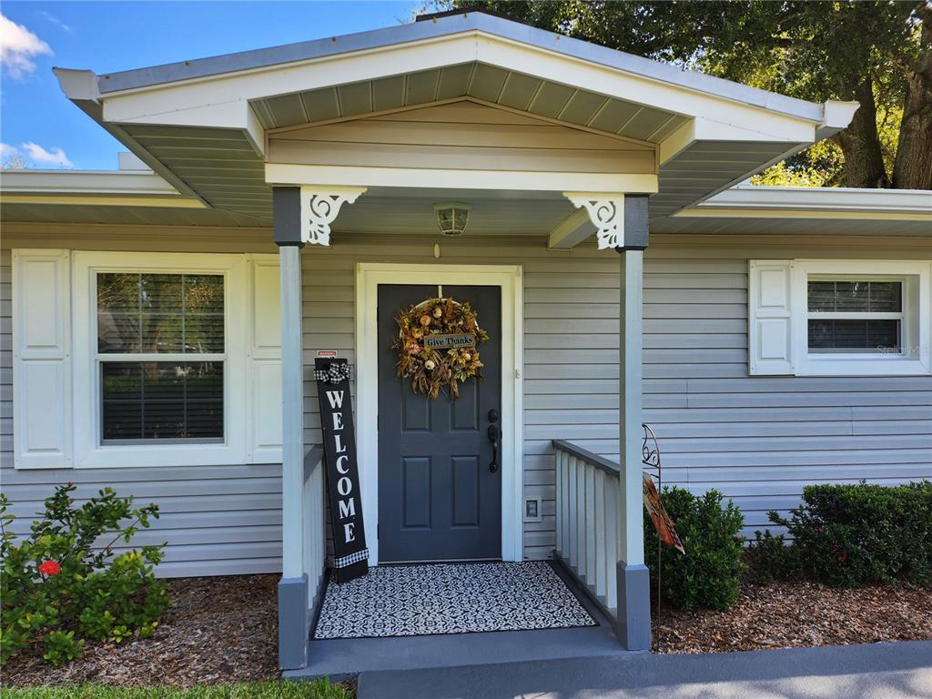 The exterior of a house features a covered front porch with a gray door — 411 BRYAN ROAD, BRANDON, FL