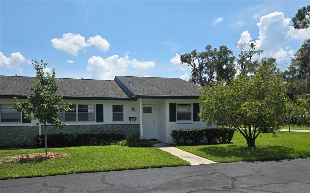 A white, single-story house with green shutters and a hedge in the front yard — 201 N HILL AVENUE UNIT 150, DELAND, FL