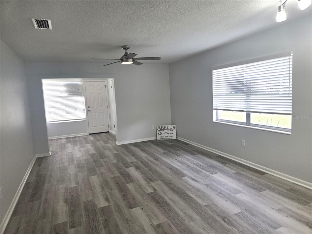 This room features light gray walls, wood-look flooring, a window with curtains, and track lighting — 201 N HILL AVENUE UNIT 150, DELAND, FL