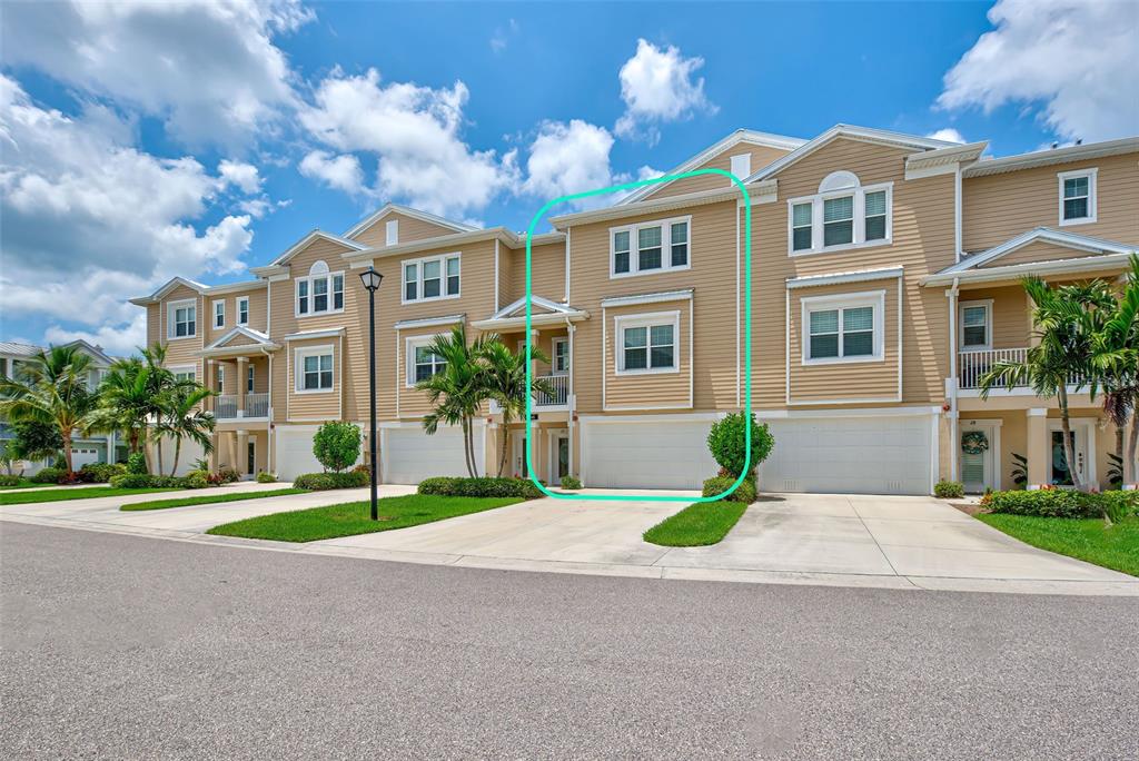 A three-story townhouse with tan siding and a two-car garage under a blue sky — 10345 LONGSHORE ROAD UNIT 29, PLACIDA, FL