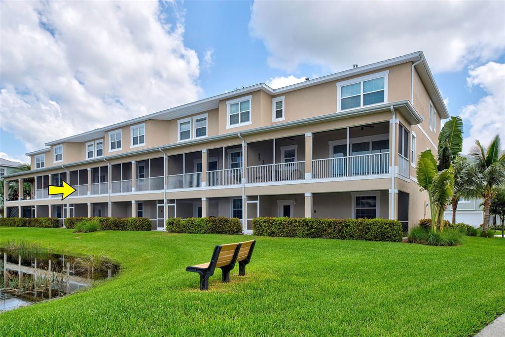 A three-story apartment building features screened-in balconies overlooking a grassy lawn and pond — 10345 LONGSHORE ROAD UNIT 29, PLACIDA, FL