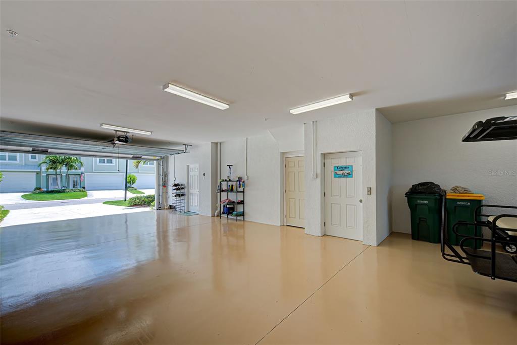 A clean, spacious garage with a light-colored epoxy floor, two white doors, and overhead lighting — 10345 LONGSHORE ROAD UNIT 29, PLACIDA, FL
