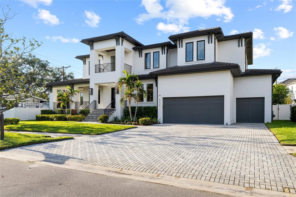 A two-story white house with a dark roof, gray garage doors, and a paved driveway — 5025 W DANTE AVENUE, TAMPA, FL