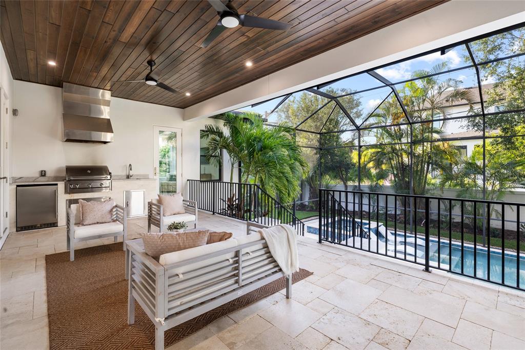 A covered outdoor patio features a kitchen, seating area, wood ceiling, and a screened pool — 5025 W DANTE AVENUE, TAMPA, FL