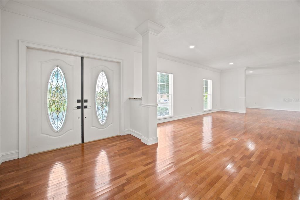 An entryway with hardwood floors, a white column, and double doors with decorative glass inserts — 7860 NW 56TH PLACE, OCALA, FL