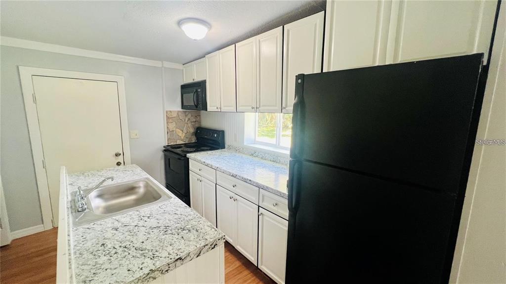 A kitchen features white cabinets, granite-look countertops, and black appliances — 1616 HOPE STREET, INTERCESSION CITY, FL