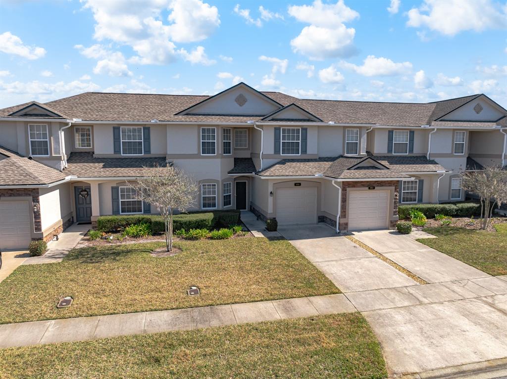 An exterior view of a multi-unit townhouse complex with beige siding and shingled roofs — 466 WOODED CROSSING CIRCLE, ST AUGUSTINE, FL