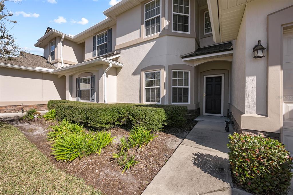 A two-story house exterior features a concrete walkway leading to a dark front door — 466 WOODED CROSSING CIRCLE, ST AUGUSTINE, FL