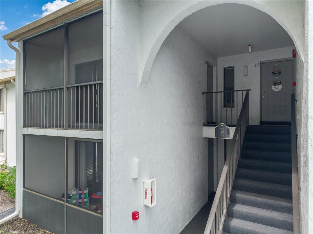 An exterior view of a multi-story apartment building with a screened balcony and stairs — 8201 SUN SPRING CIRCLE UNIT C2, ORLANDO, FL