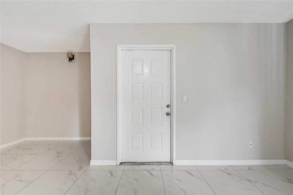 A white door with eight panels is centered on a light gray wall above tiled floors — 8201 SUN SPRING CIRCLE UNIT C2, ORLANDO, FL