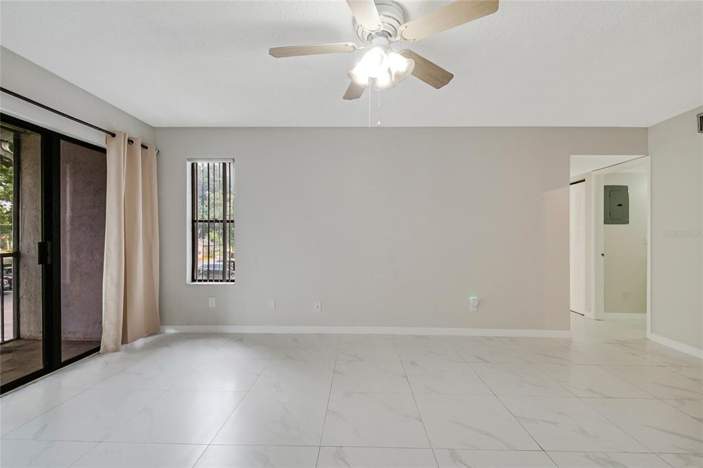 A bright living room features white tile flooring, a ceiling fan, and a sliding glass door — 8201 SUN SPRING CIRCLE UNIT C2, ORLANDO, FL