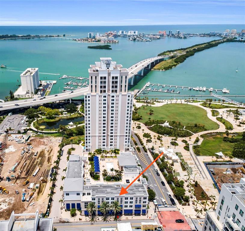 An aerial view shows a tall residential tower and adjacent low-rise buildings near a bridge — 331 CLEVELAND STREET UNIT 312, CLEARWATER, FL