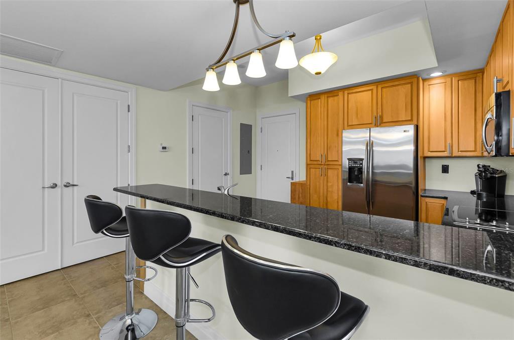 A kitchen with wood cabinets, stainless steel appliances, and a black granite breakfast bar — 331 CLEVELAND STREET UNIT 312, CLEARWATER, FL