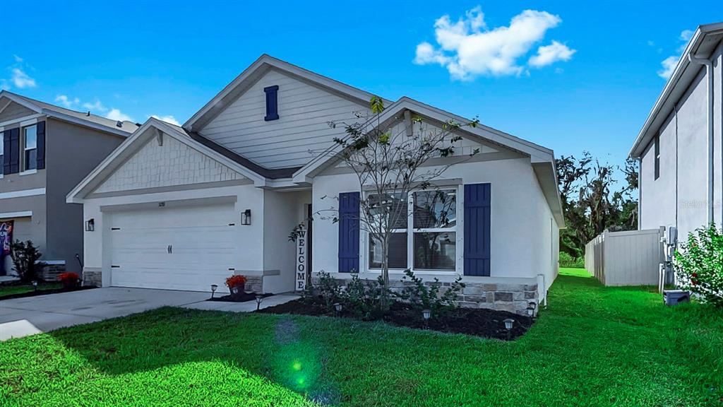 A single-story house with a white stucco exterior, blue shutters, and a two-car garage — 3281 SILVER DATE DRIVE, WIMAUMA, FL