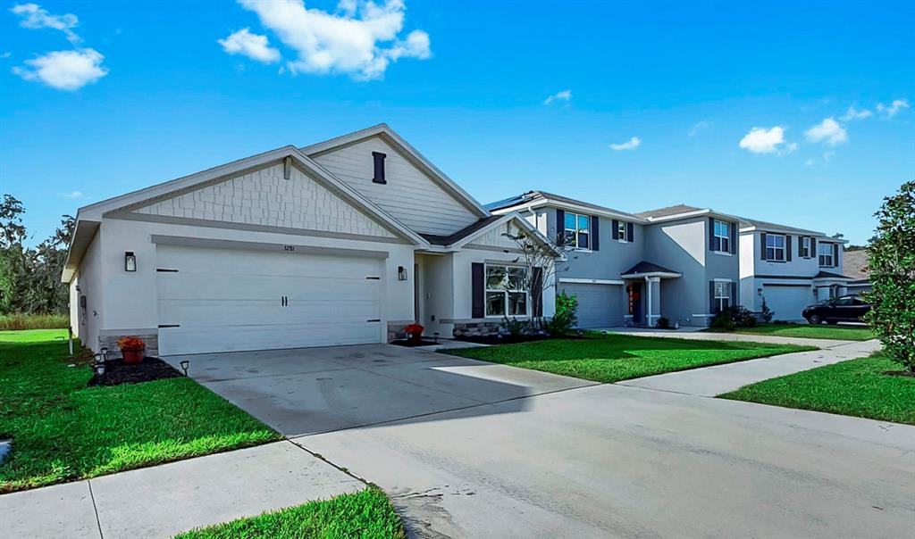 A single-story suburban house with a two-car garage and a light-colored exterior — 3281 SILVER DATE DRIVE, WIMAUMA, FL