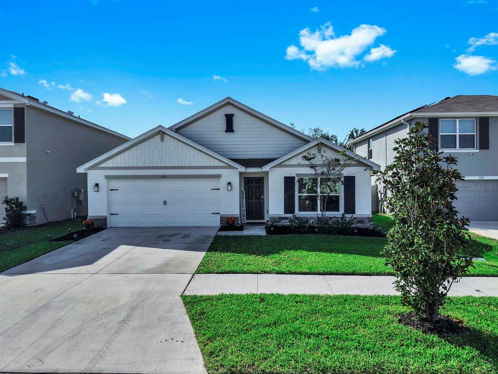 A single-story suburban house with a two-car garage, light siding, and a front lawn — 3281 SILVER DATE DRIVE, WIMAUMA, FL