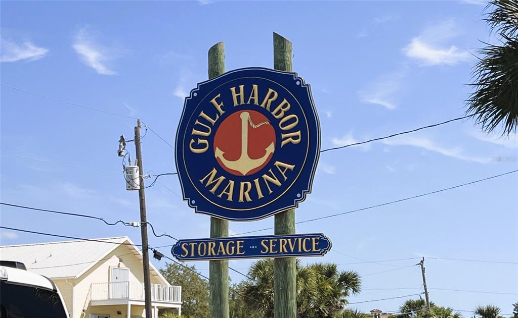 A blue sign for Gulf Harbor Marina stands on wooden posts against a blue sky — 100 CIRCUIT ROAD UNIT S101, NOKOMIS, FL