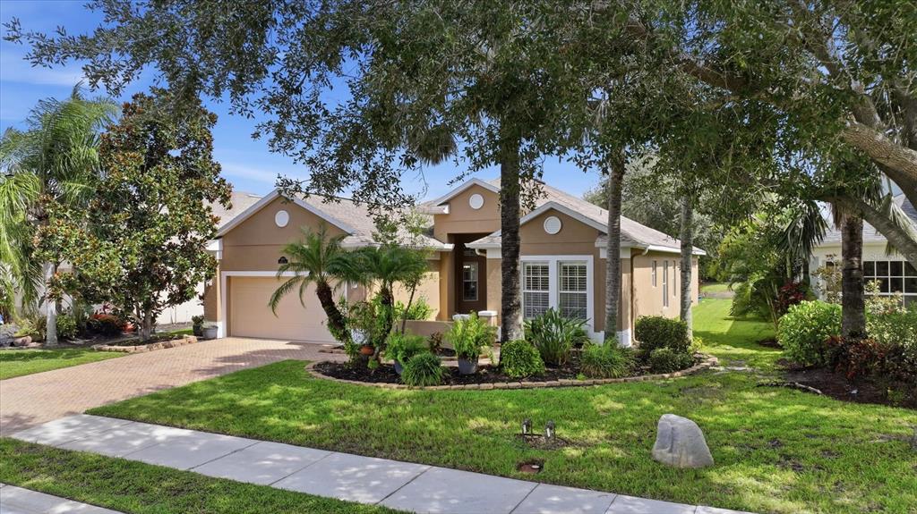 A single-story tan house with a two-car garage and a landscaped front yard — 12231 LAVENDER LOOP, BRADENTON, FL