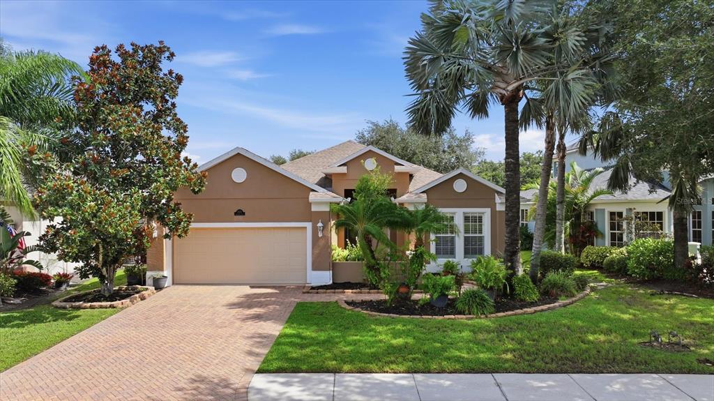 A single-story tan house with a two-car garage and a brick paver driveway — 12231 LAVENDER LOOP, BRADENTON, FL