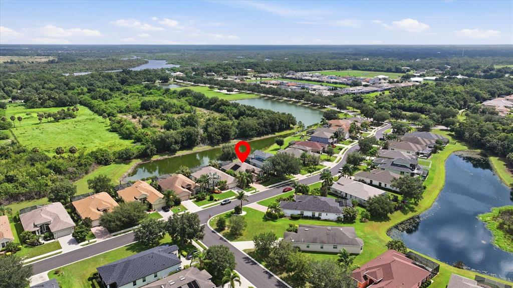 An aerial view shows a suburban neighborhood with houses, ponds, and green space — 12231 LAVENDER LOOP, BRADENTON, FL