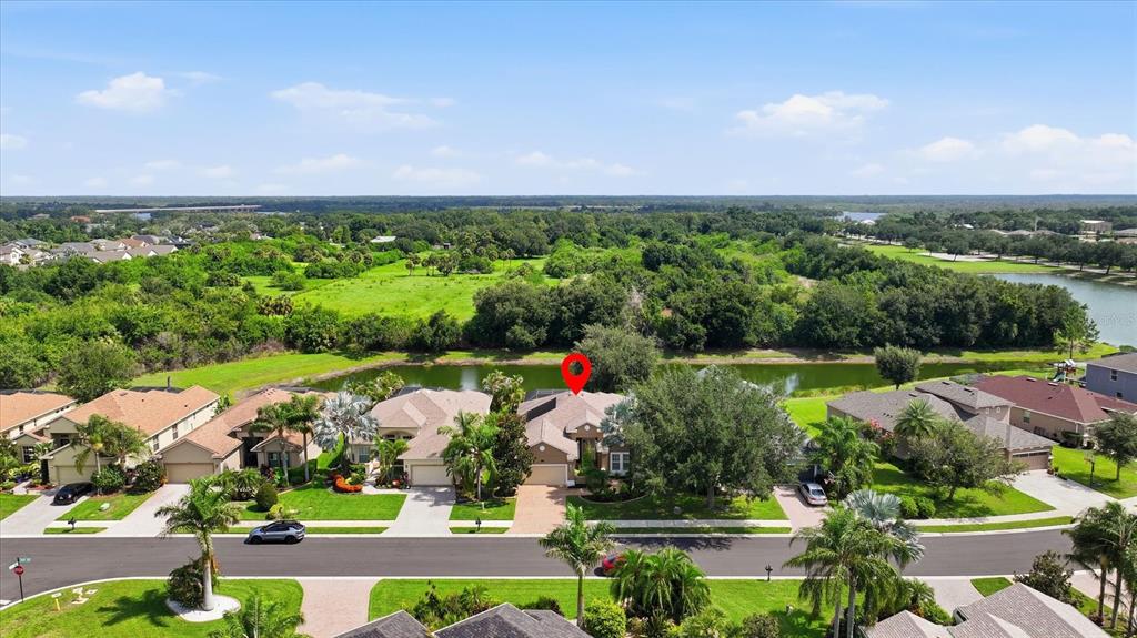 An aerial view shows a suburban house with a red location pin and backyard pond — 12231 LAVENDER LOOP, BRADENTON, FL