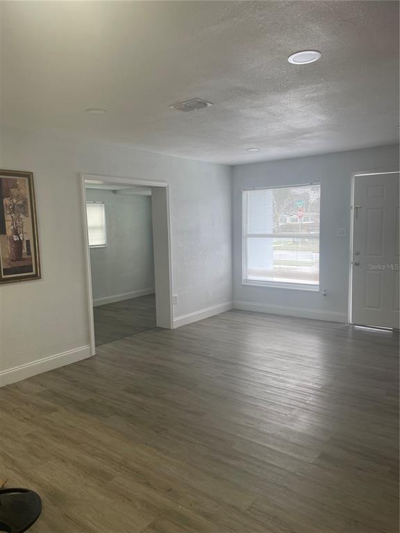 An empty room with light wood-look flooring, recessed lighting, and a doorway to another room — 519 DENSON STREET, COCOA, FL