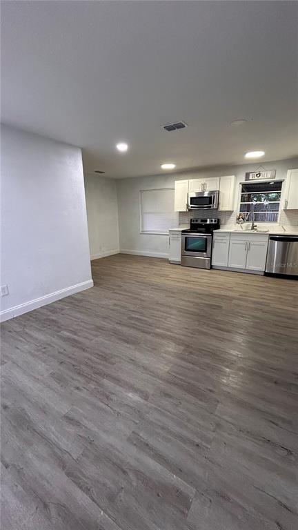 A kitchen with white cabinets and stainless steel appliances opens to a spacious living area — 519 DENSON STREET, COCOA, FL