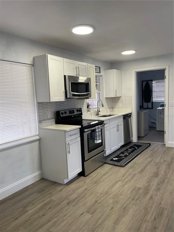 A kitchen features white cabinets, stainless steel appliances, and light wood-look flooring — 519 DENSON STREET, COCOA, FL