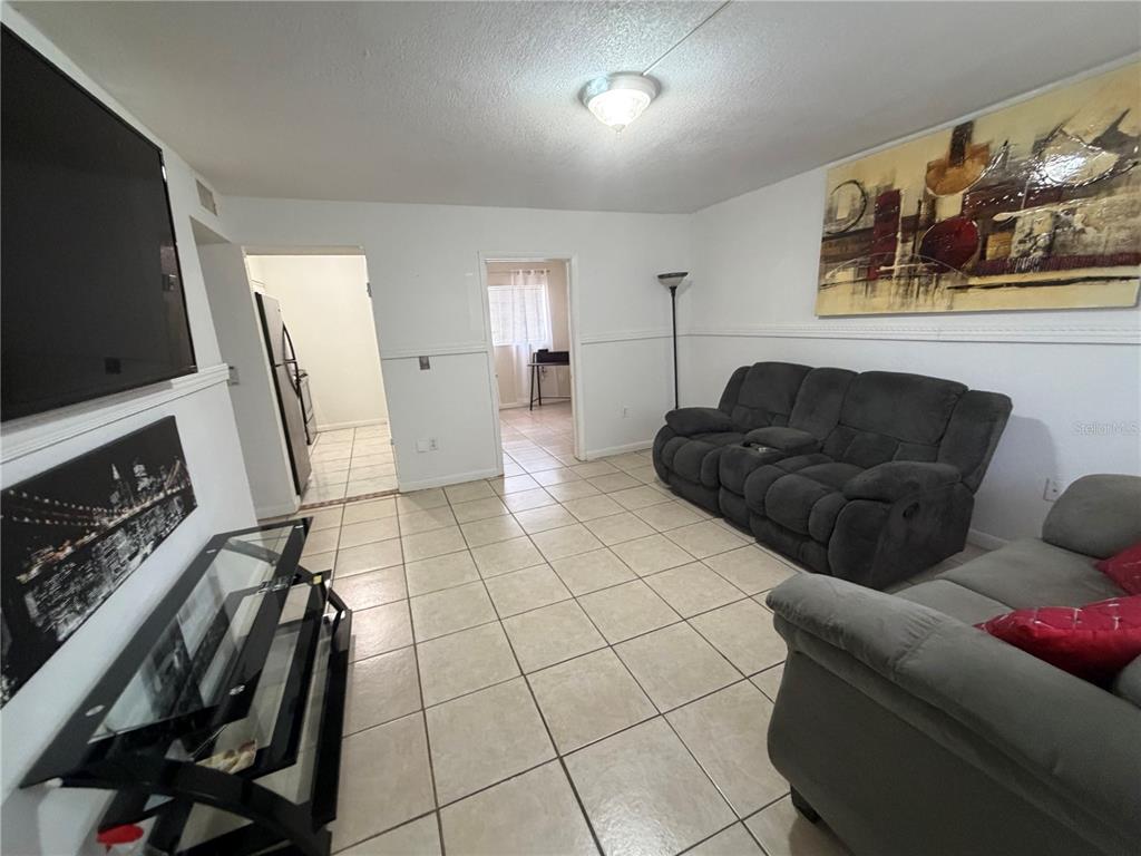 A narrow kitchen features white cabinets, a black refrigerator, and light-colored tiled flooring — 738 RIDENHOUR CIRCLE UNIT L, ORLANDO, FL