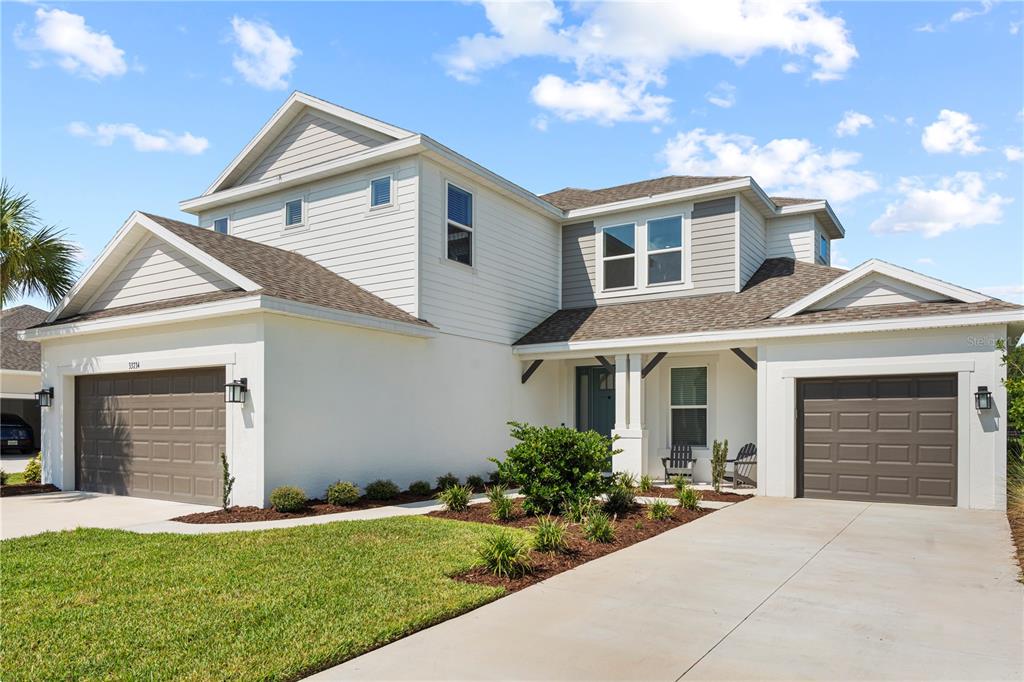 A two-story house with white stucco, gray siding, two garages, and a front porch — 33734 LANDSMAN LOOP, WESLEY CHAPEL, FL