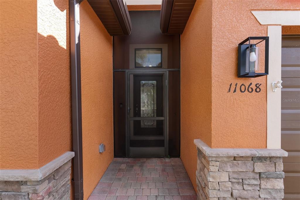 The front entrance features a screen door, stone accents, and a wall-mounted light fixture — 11068 CHERRY LAUREL DR., FORT MYERS, FL
