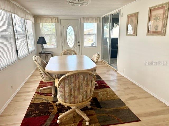 A dining area features a wooden table, four chairs, and a patterned rug on light flooring — 294 COLONIAL BOULEVARD UNIT 48, PALM HARBOR, FL